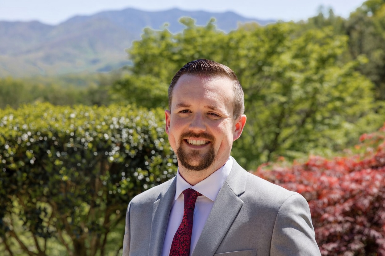 Jordan Patterson in a gray suit and wine-colored tie outdoors